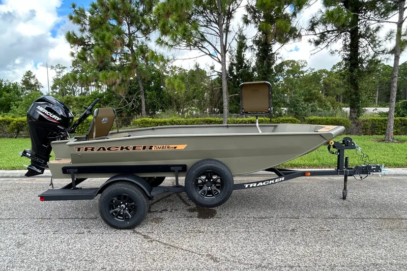 The Image of 2027 Tracker Grizzly 1553 Timber boat on trailer, parked outdoors with trees in background. - 0