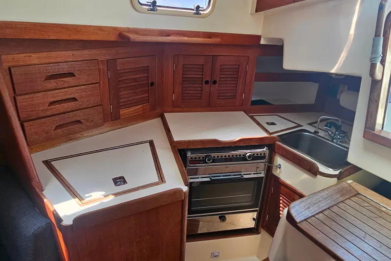 Slide: The Image of 1994 Tartan 3100 yacht kitchen with wooden cabinets, stove, and sink. - 21