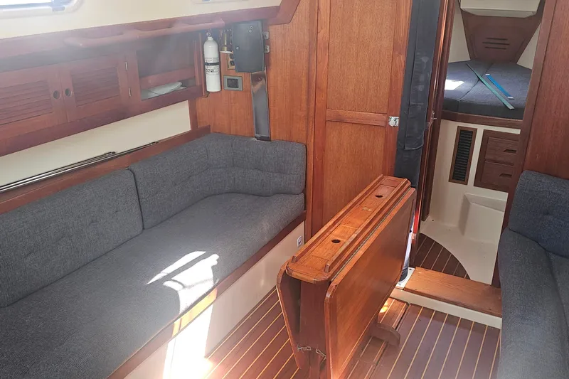 Slide: The Image of Cozy interior of a 1994 Tartan 3100 sailboat with wooden furnishings and gray seating. - 10
