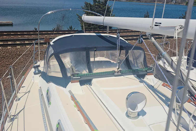 Slide: The Image of 1994 Tartan 3100 sailboat with blue canopy, docked near a serene waterfront. - 5