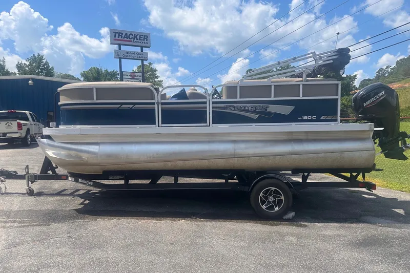 The Image of 2020 Ranger 180C pontoon boat on trailer, parked outdoors under a blue sky. - 0