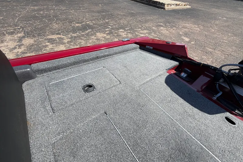 Slide: The Image of 2023 Bass Tracker Pro 17 boat deck with gray carpeting and red trim. - 28