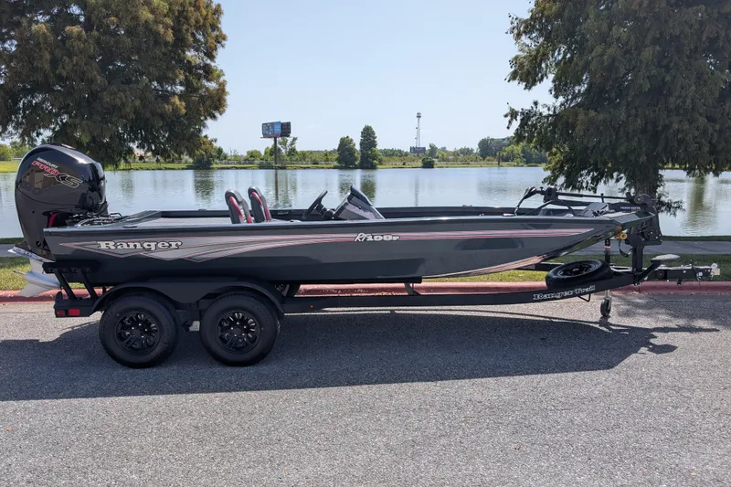 Slide: The Image of 2027 Ranger RT198P boat on trailer by a serene lake, under clear skies. - 1