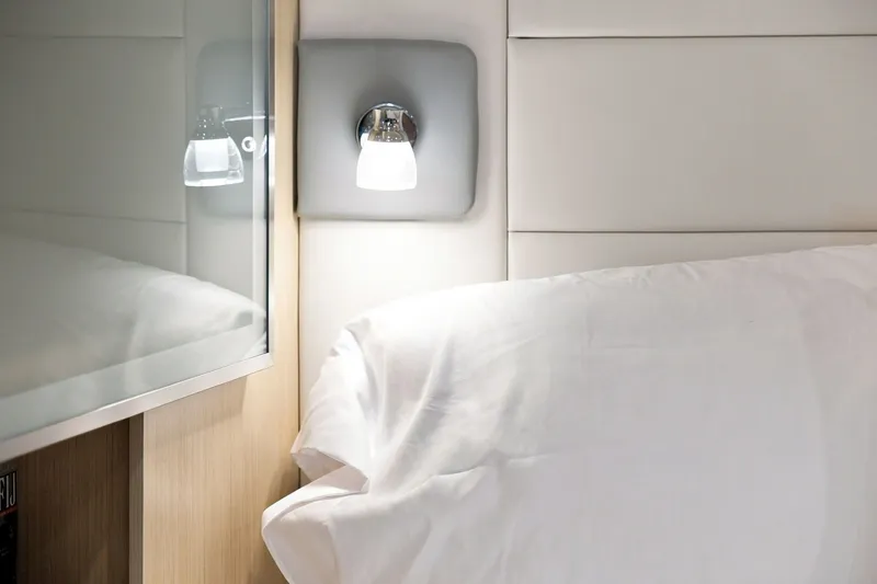 Slide: The Image of Interior of 2025 Regal 42 Grande Coupe with modern wall light and plush bedding. - 26