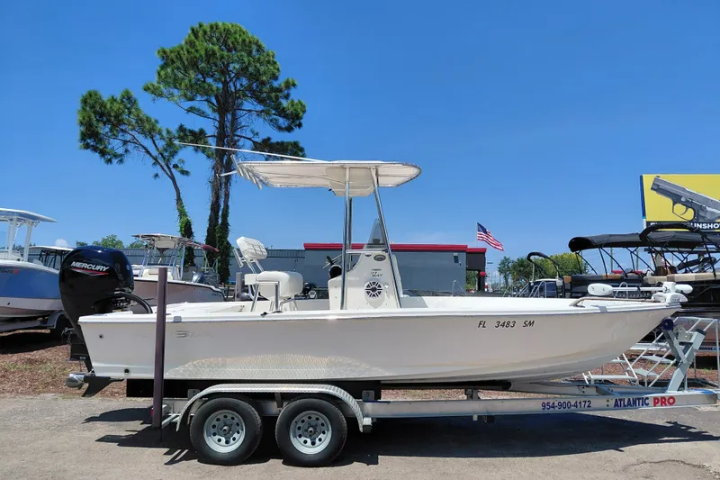 Slide: The Image of 2020 Cobia 21 Bay boat on trailer, parked outdoors under clear blue sky. - 11