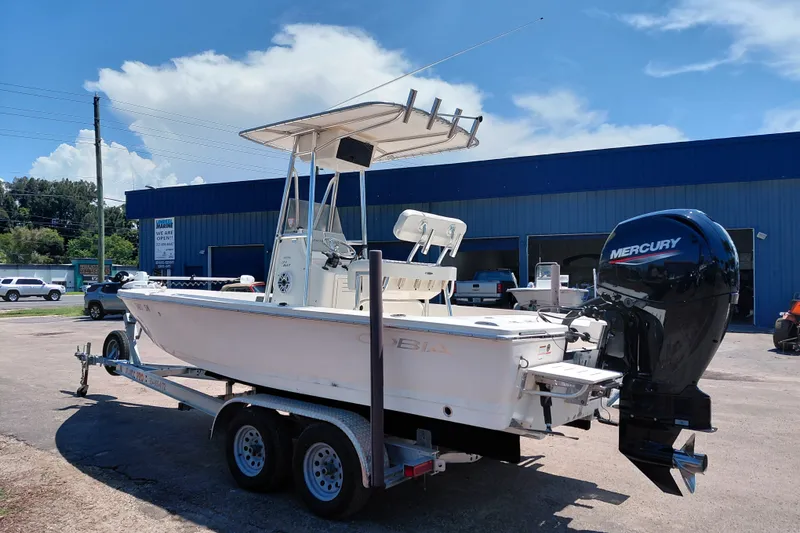 Slide: The Image of 2020 Cobia 21 Bay boat with Mercury engine on trailer, parked outside a blue building. - 5