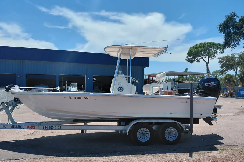 Slide: The Image of 2020 Cobia 21 Bay boat on trailer, parked outside a blue building under a clear sky. - 4