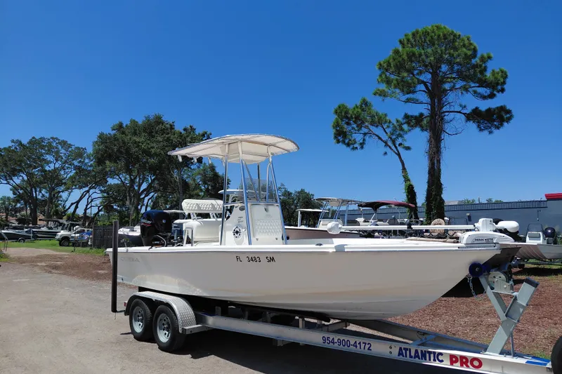 The Image of 2020 Cobia 21 Bay boat on trailer, parked outdoors under clear blue sky. - 1