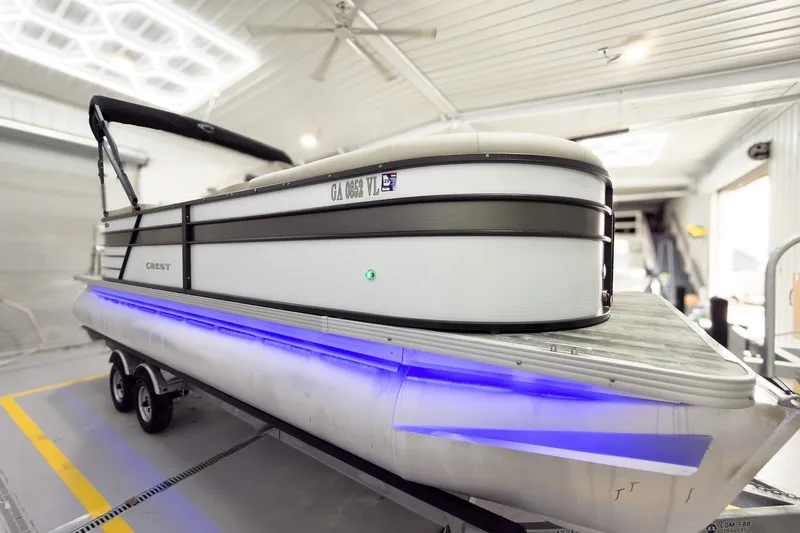 The Image of 2021 Crest Classic DLX 220 SLC pontoon boat with blue LED lights in a garage. - 0