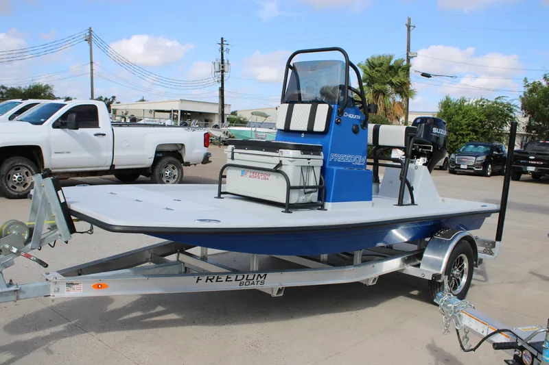 Slide: The Image of 2027 Freedom Boats Chiquita on trailer, parked outdoors with vehicles in the background. - 3