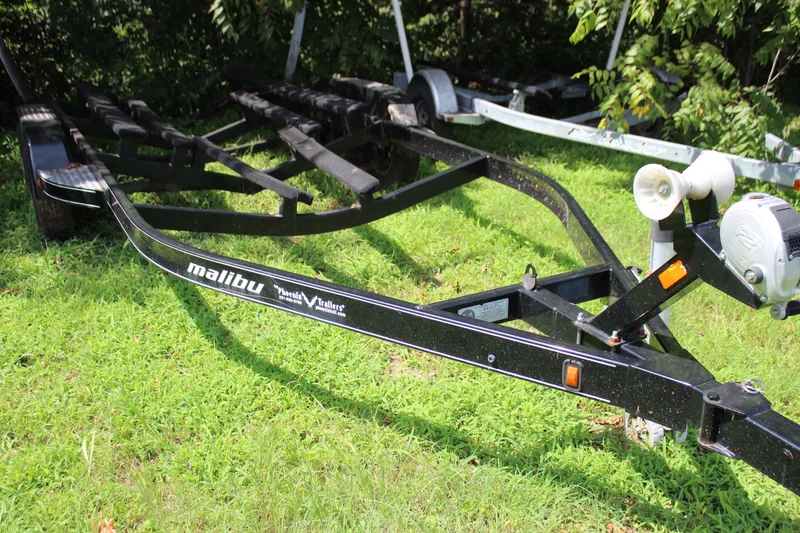 Slide: The Image of Trailer for 2015 Malibu Wakesetter 22 VLX on grass, surrounded by trees. - 38