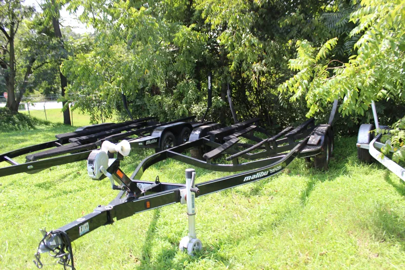 Slide: The Image of Trailer for 2015 Malibu Wakesetter 22 VLX boat parked on grass near trees. - 55