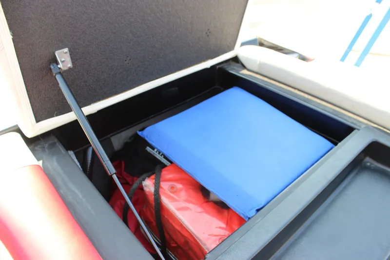 Slide: The Image of Storage compartment in a 2015 Malibu Wakesetter 22 VLX boat with blue and red items. - 16