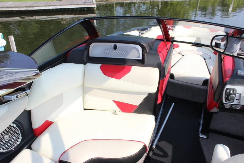 Slide: The Image of 2015 Malibu Wakesetter 22 VLX boat interior with red and white seating by the water. - 12