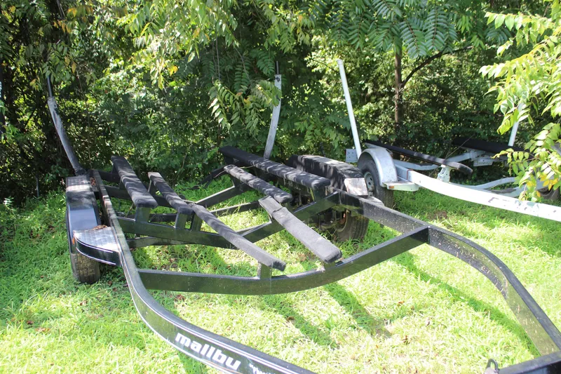 Slide: The Image of Trailer for 2015 Malibu Wakesetter 22 VLX boat, parked on grass near trees. - 37