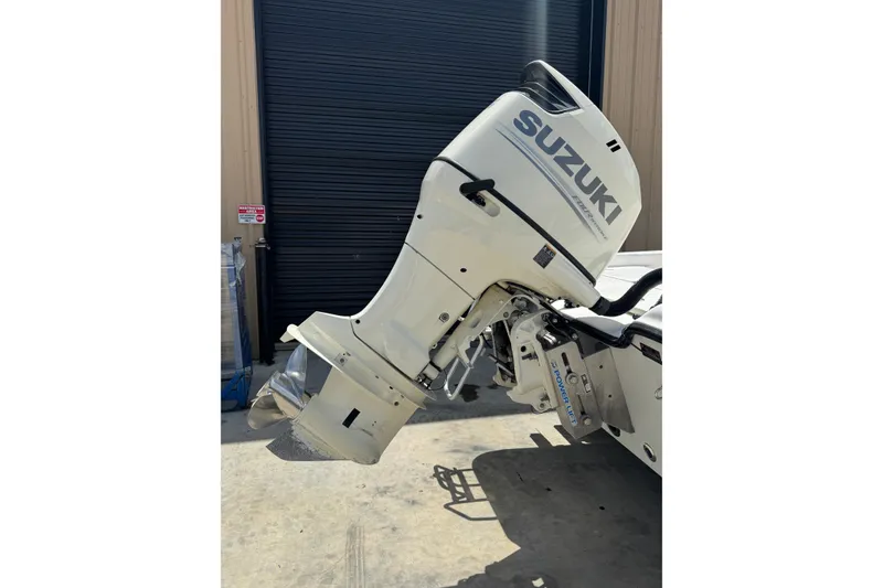 Slide: The Image of 2018 Blue Wave 2200 PureBay boat with Suzuki outboard motor in a garage setting. - 17