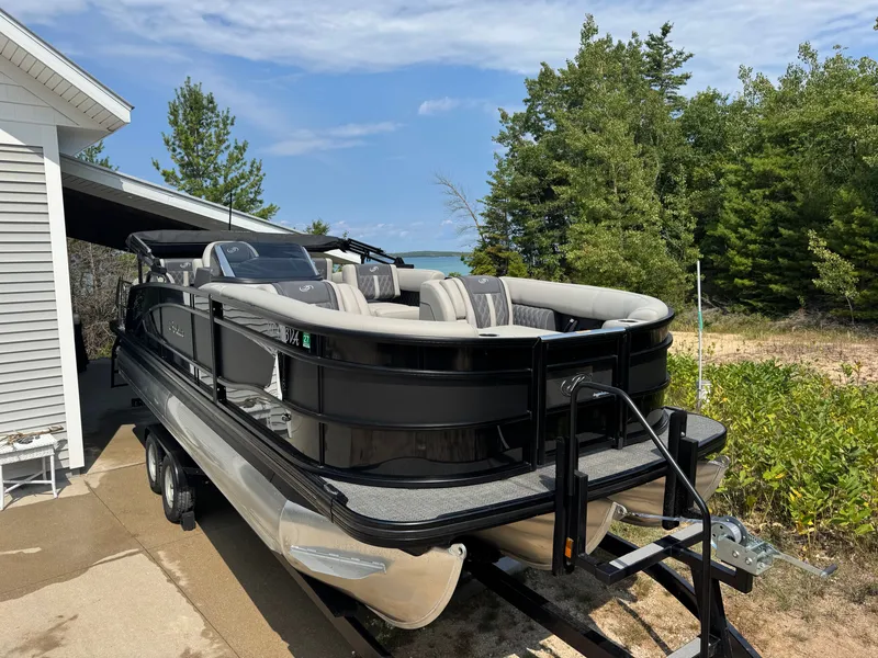 Slide: The Image of A sleek pontoon boat with luxurious seating, parked beside a building, surrounded by trees. - 9