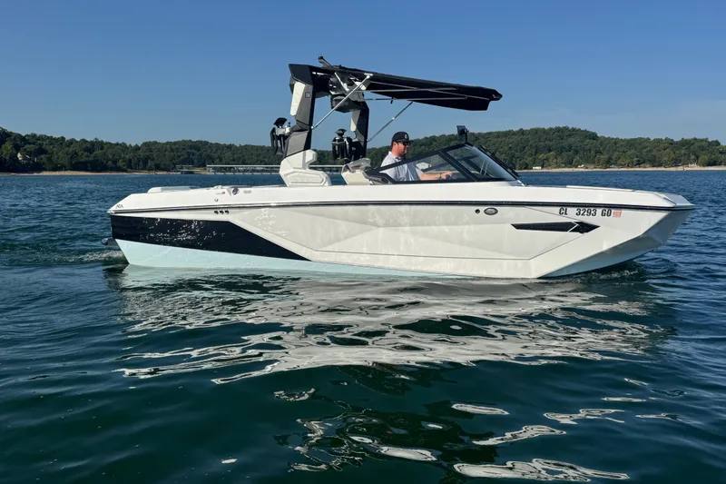 The Image of 2023 Nautique Super Air Nautique G23 boat cruising on a serene lake. - 1