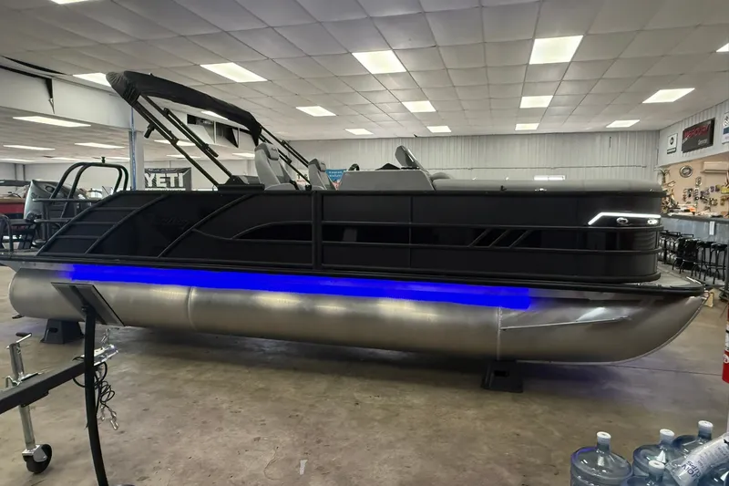 Slide: The Image of 2026 Bentley Pontoons Elite 223 Swingback with sleek design and blue underglow lighting in showroom. - 2