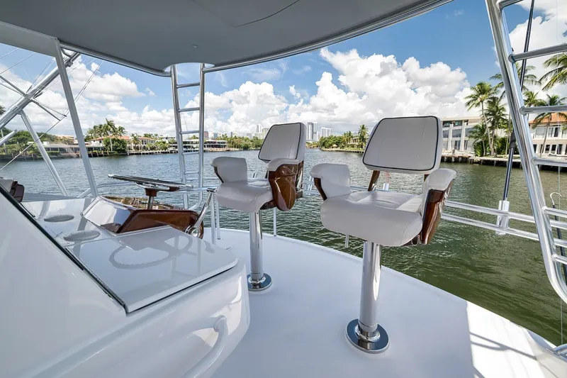 Slide: The Image of 2021 Hatteras GT65 Carolina yacht helm with luxurious seating and scenic waterfront view. - 22