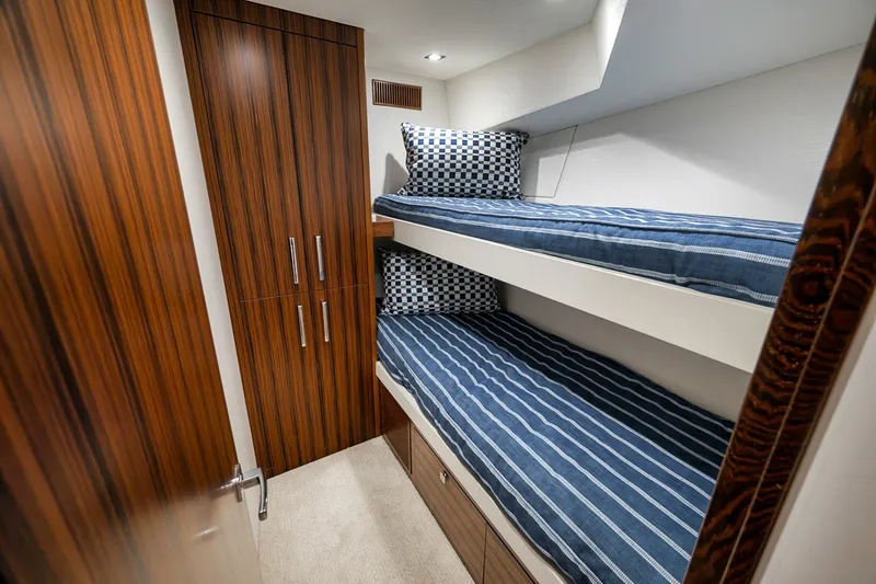 Slide: The Image of 2021 Hatteras GT65 Carolina yacht cabin with bunk beds and wood cabinetry. - 44