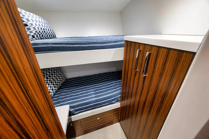 Slide: The Image of 2021 Hatteras GT65 Carolina yacht cabin with bunk beds and wooden cabinetry. - 47