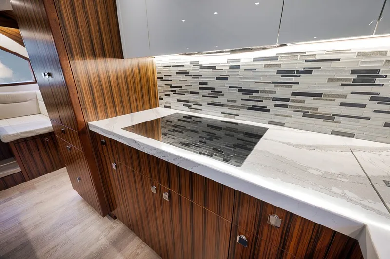Slide: The Image of Luxurious kitchen interior of 2021 Hatteras GT65 Carolina yacht with modern backsplash and wood cabinetry. - 36