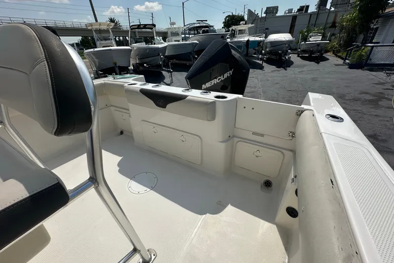 Slide: The Image of 2023 Sailfish 242 CC boat interior with Mercury engine, docked among other boats. - 10