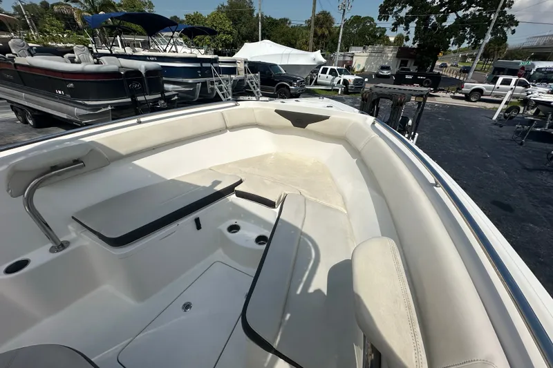 Slide: The Image of 2023 Sailfish 242 CC boat interior with seating and storage, parked in a marina. - 16