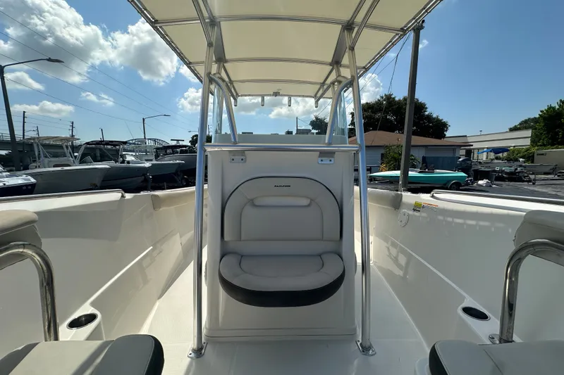Slide: The Image of 2023 Sailfish 242 CC boat interior with seating and canopy under a sunny sky. - 17