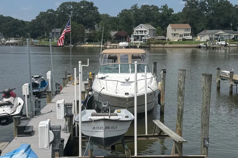 Slide: The Image of A 2006 Cruisers Yachts 370 Express docked at a serene pier with surrounding houses. - 1