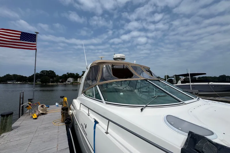 Slide: The Image of 2006 Cruisers Yachts 370 Express docked by a lake with American flag. - 4