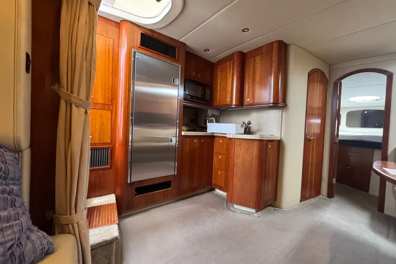 Slide: The Image of Interior of 2006 Cruisers Yachts 370 Express, featuring a modern kitchen with wood cabinetry. - 22