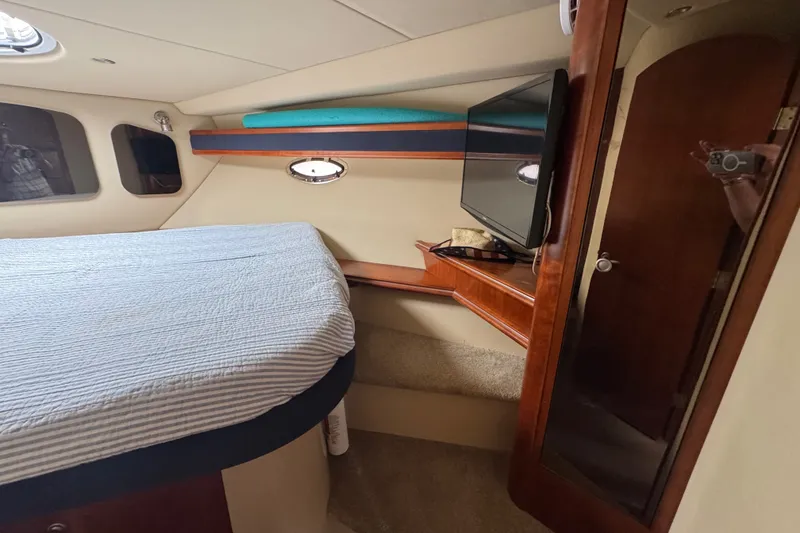 Slide: The Image of 2006 Cruisers Yachts 370 Express cabin interior with bed, TV, and wooden accents. - 30