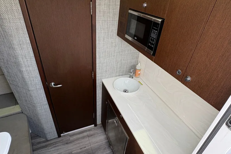 Slide: The Image of Interior of 2023 Everglades 455 Center Console with sink, microwave, and wooden cabinetry. - 41