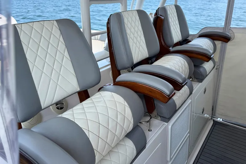 Slide: The Image of Luxurious seating on 2023 Everglades 455 Center Console boat, featuring quilted upholstery and wooden armrests. - 28