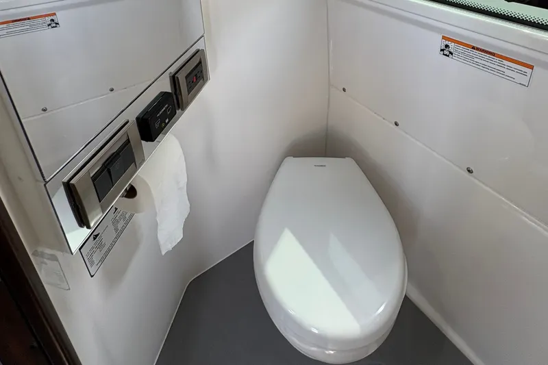 Slide: The Image of 2023 Everglades 455 Center Console boat bathroom with modern toilet and control panel. - 43