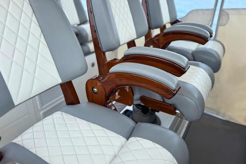 Slide: The Image of Luxury seating on 2023 Everglades 455 Center Console boat, featuring quilted upholstery and wooden armrests. - 36