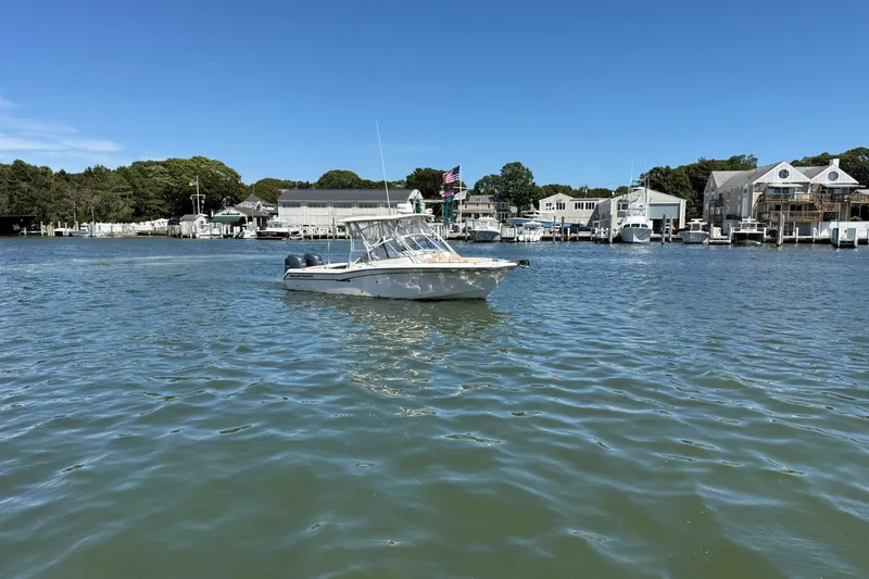 Slide: The Image of 2013 Grady-White Freedom 255 boat on calm water near a marina. - 2
