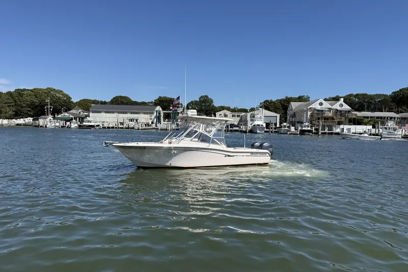 Slide: The Image of 2013 Grady-White Freedom 255 boat on calm water near marina buildings. - 5