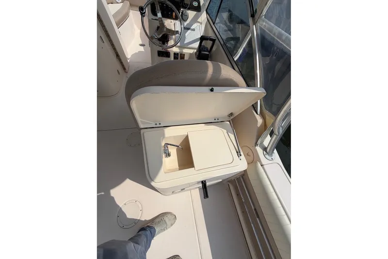 Slide: The Image of 2013 Grady-White Freedom 255 boat interior with open storage compartment and steering wheel. - 22