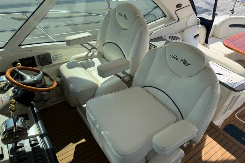 Slide: The Image of 2005 Sea Ray 48 Sundancer helm with white leather seats and wooden steering wheel. - 38