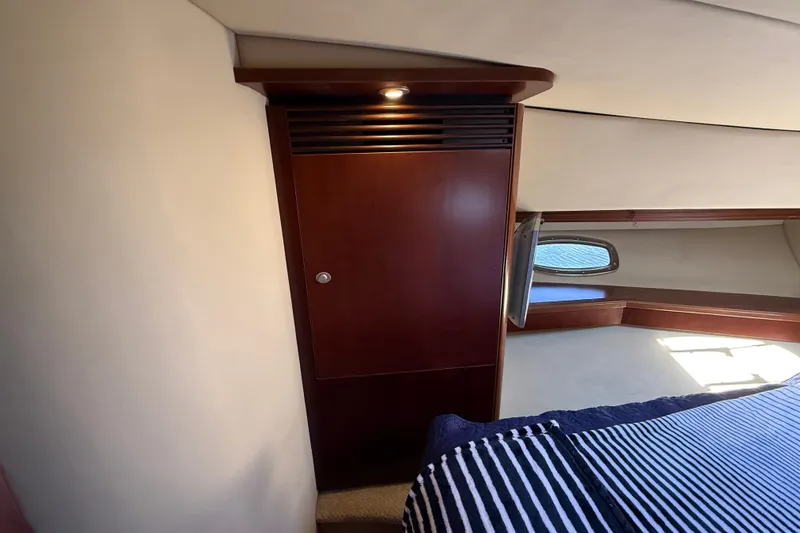 Slide: The Image of Interior cabin of 2005 Sea Ray 48 Sundancer yacht with wooden cabinetry and striped bedding. - 50
