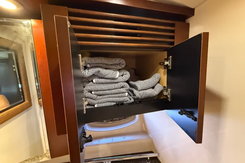 Slide: The Image of Open cabinet with folded striped towels inside a 2005 Sea Ray 48 Sundancer yacht. - 60