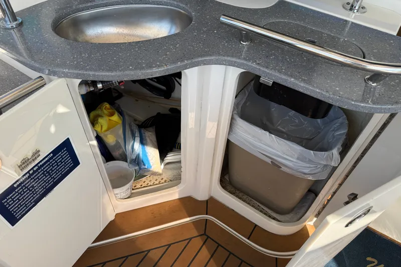 Slide: The Image of 2005 Sea Ray 48 Sundancer yacht interior with sink, storage, and trash bin. - 17