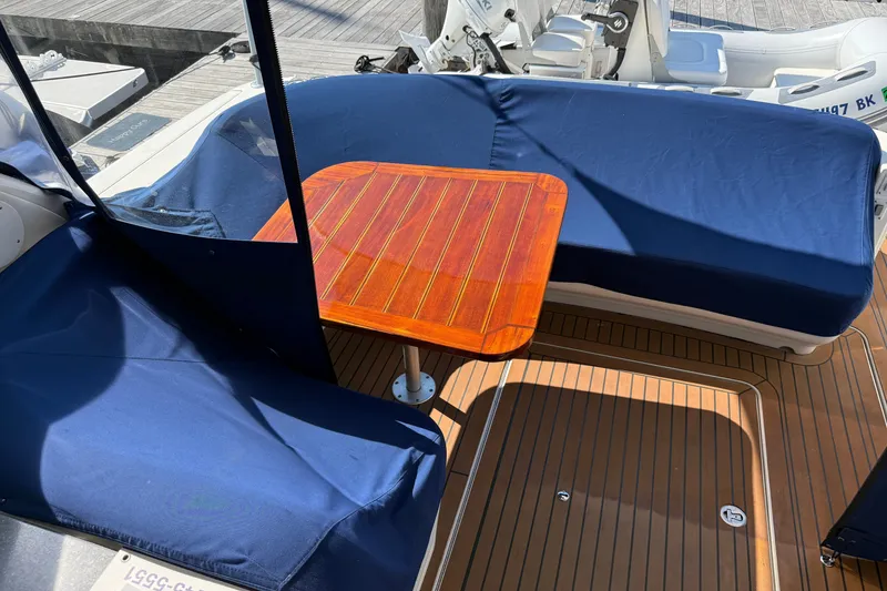 Slide: The Image of 2005 Sea Ray 48 Sundancer cockpit with blue seating and wooden table. - 9