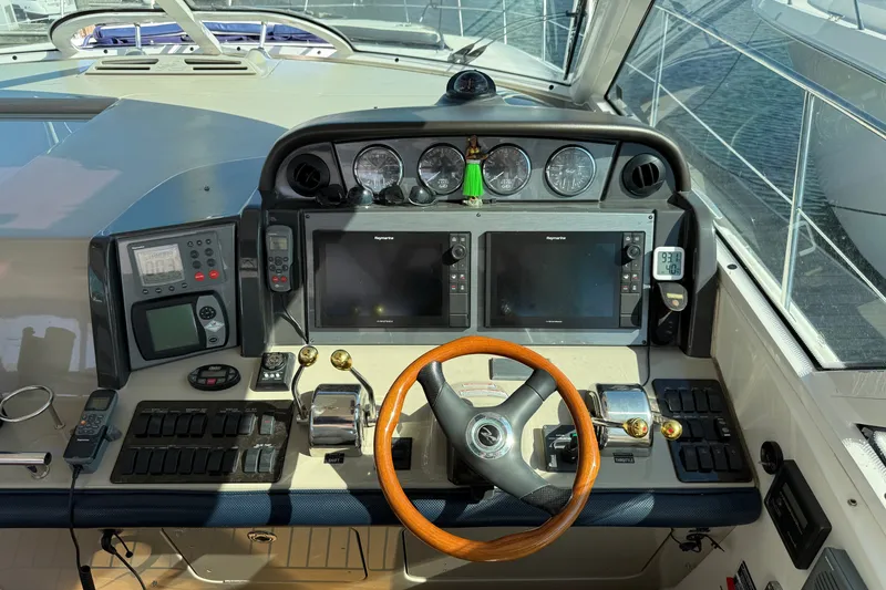 Slide: The Image of 2005 Sea Ray 48 Sundancer helm with navigation controls and wooden steering wheel. - 39