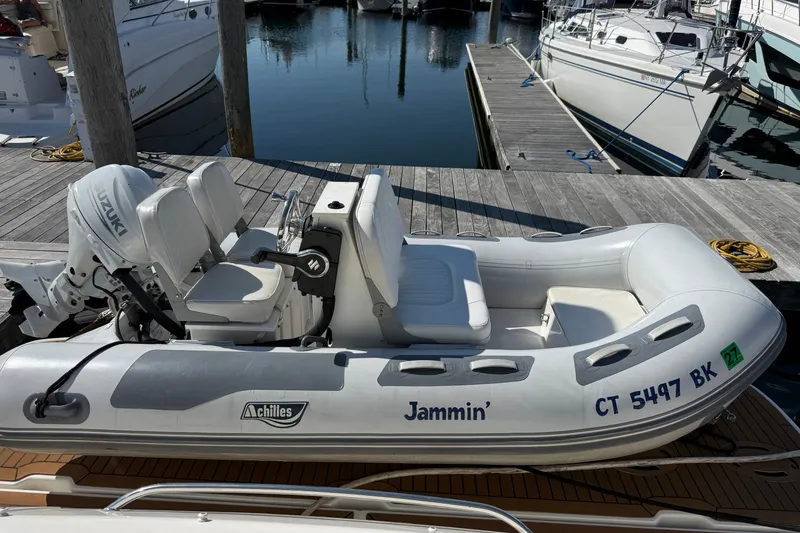 Slide: The Image of Inflatable boat "Jammin'" docked, featuring Suzuki motor, near Sea Ray 48 Sundancer, 2005 model. - 5