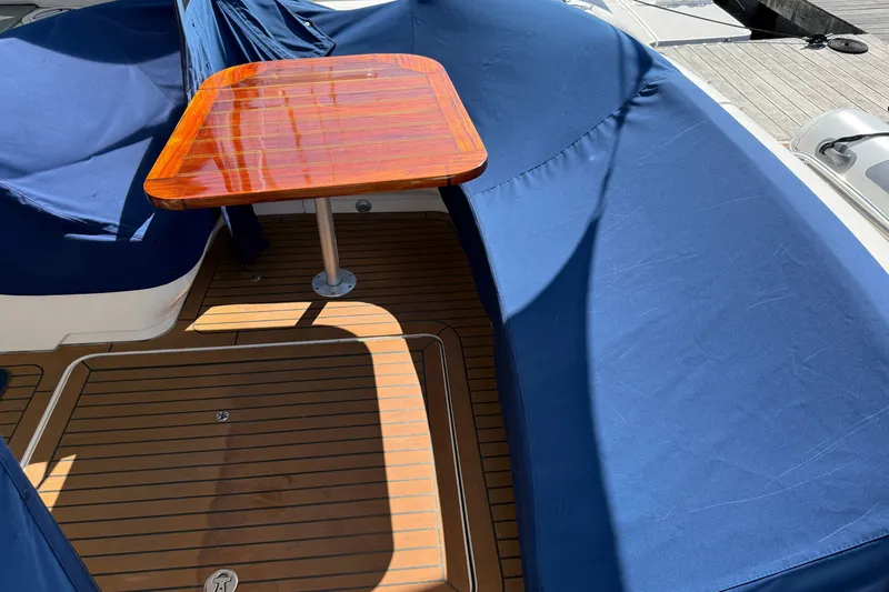 Slide: The Image of 2005 Sea Ray 48 Sundancer yacht deck with blue seating and wooden table. - 8
