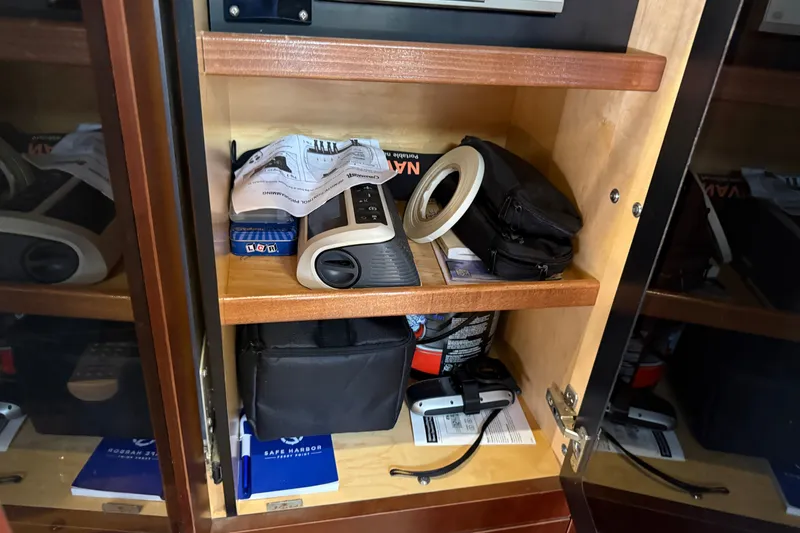 Slide: The Image of Storage cabinet on 2005 Sea Ray 48 Sundancer yacht with various items and manuals. - 88